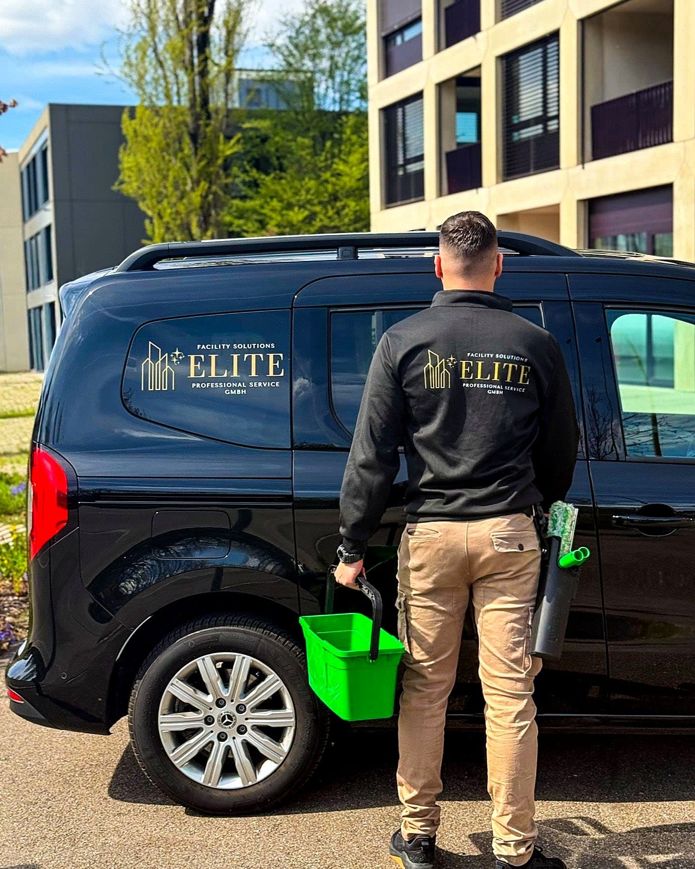 Mitarbeiter von Elite Professional Service mit Fensterreinigungsausrüstung beim Firmenfahrzeug
